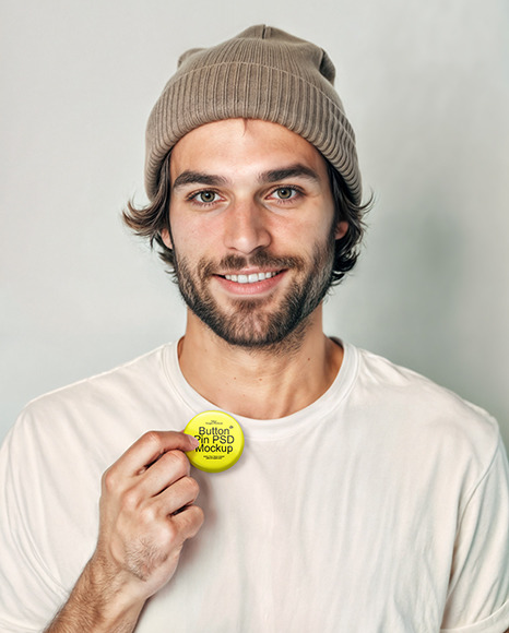 Man Wearing a T-Shirt and Beanie Hat Holding a Button Pin Mockup